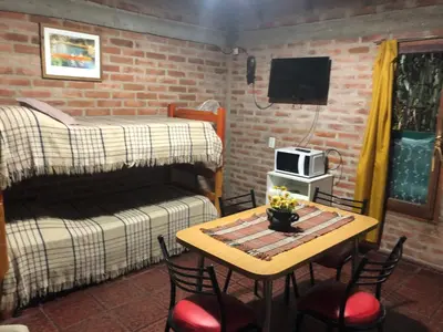 a small room with a table and a bed and a table and chairs at Cabaña en el centro La Casona in Mina Clavero