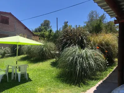 a patio with an umbrella and a table and chairs at Cabaña en el centro La Casona in Mina Clavero