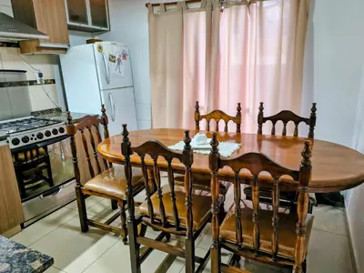 a kitchen with a wooden table with chairs and a refrigerator at Fidelita in Villa Carlos Paz