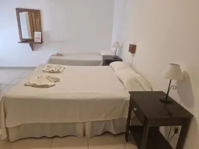 a bedroom with two beds and a table with a lamp at Hotel Maspalomas in Villa Carlos Paz