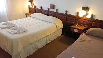 a hotel room with two beds and two tables at Hotel Maspalomas in Villa Carlos Paz