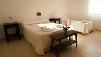 a hotel room with two beds and two tables at Hotel Maspalomas in Villa Carlos Paz