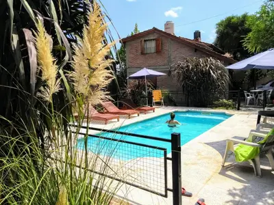 a person in a swimming pool next to a house at Cabaña La Casona en el centro in Mina Clavero