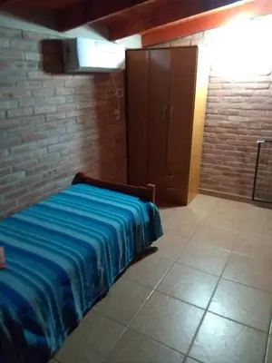 a bed in a room with a brick wall at Cabaña La Casona en el centro in Mina Clavero