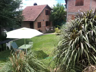 a white table and an umbrella in a yard at Cabaña La Casona en el centro in Mina Clavero