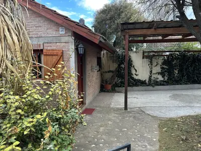 a backyard with a brick building and a wooden pergola at Cabaña La Casona en el centro in Mina Clavero
