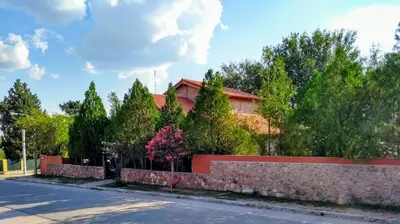 a house with a stone fence in front of a street at Cabaña La Casona en el centro in Mina Clavero