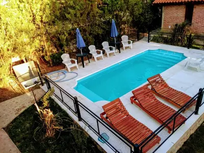 a swimming pool with chairs and umbrellas at Cabaña La Casona en el centro in Mina Clavero