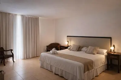 a bedroom with a large white bed with two lamps at Panacea Hotel in Villa General Belgrano
