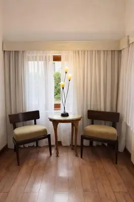a room with two chairs and a table with a lamp at Panacea Hotel in Villa General Belgrano