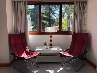 two chairs and a table in a room with a window at Panacea Hotel in Villa General Belgrano