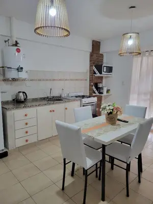 a kitchen with a table with white chairs and a counter at Departamento Urquiza2 in Alta Gracia