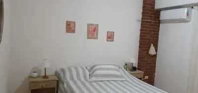 a bed in a white room with two night stands and two pictures at Departamento Urquiza2 in Alta Gracia