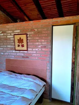 a bedroom with a brick wall with a bed and a door at La Serranita in Panaholma