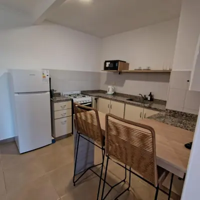 a kitchen with a white refrigerator and a table and chairs at 25 de Mayo Clínicas cerca in Cordoba