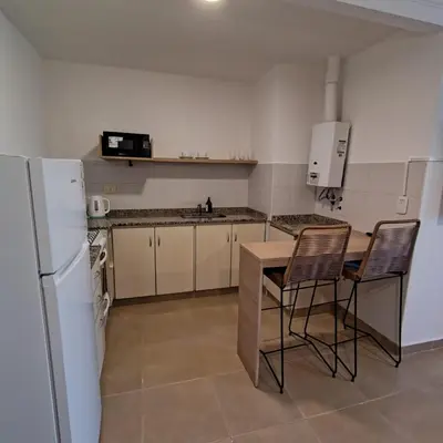 a kitchen with a white refrigerator and a table and chairs at 25 de Mayo Clínicas cerca in Cordoba