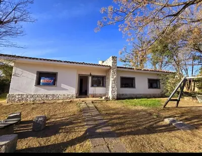 a small white house with a yard at Cazona Villa Carmen in Villa Carlos Paz