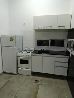 a kitchen with white cabinets and a stove and refrigerator at Sinaí Apart in Santa Rosa de Calamuchita