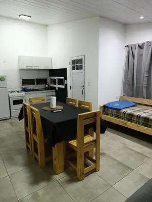 a room with a table and a kitchen with a bed at Sinaí Apart in Santa Rosa de Calamuchita