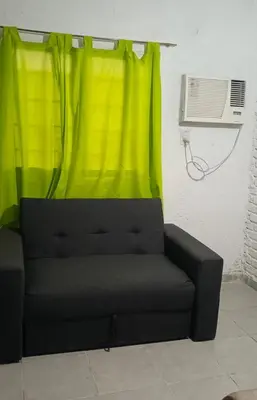 a black couch in a room with a green curtain at La morada in Cordoba