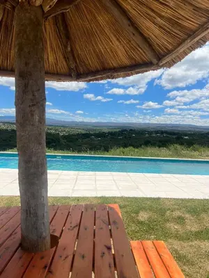 a wooden bench sitting under a thatched roof at Villa alpina in Bialet Massé