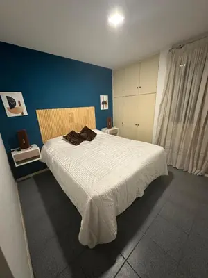 a bedroom with a large white bed with a blue wall at Departamento Nueva Córdoba in Cordoba