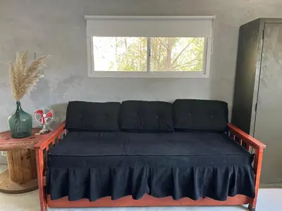 a couch sitting in a room with a window at Terrazas del Pinar, Loft con pileta exclusiva en bosque serrano in Villa Ciudad de America