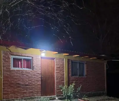 a brick house with a wooden door at night at Casa Sol Y Rio in Mina Clavero