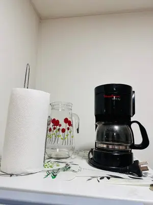 a coffee maker and a glass jar with flowers on it at Departamento premium, ubicación céntrica, Patio Olmos! in Cordoba