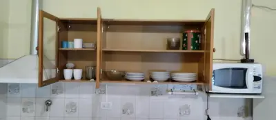 a kitchen with wooden cabinets with plates and a microwave at Cabaña Don Fernando in Los Hornillos