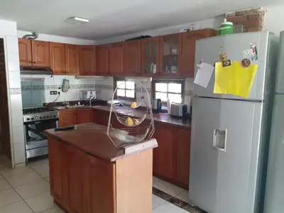 a kitchen with wooden cabinets and a white refrigerator at Rincon del sol in Villa Carlos Paz