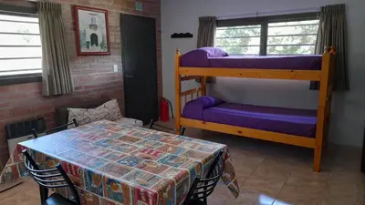 a room with two bunk beds and a table at Depto deluxe frente al río in San Antonio de Arredondo