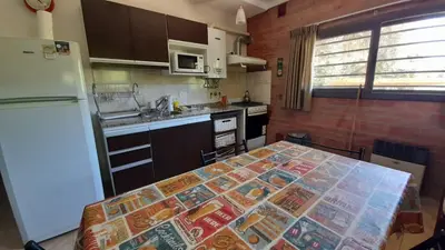 a kitchen with a table and a white refrigerator at Depto deluxe frente al río in San Antonio de Arredondo