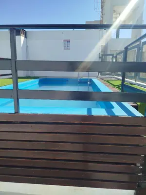 a wooden bench in front of a swimming pool at Departamento Baratti's in Villa Carlos Paz