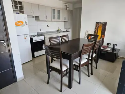a kitchen with a table and chairs and a refrigerator at Departamento Baratti's in Villa Carlos Paz