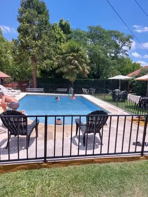 a swimming pool with two people swimming in it at Complejo Villa del sol in Mina Clavero