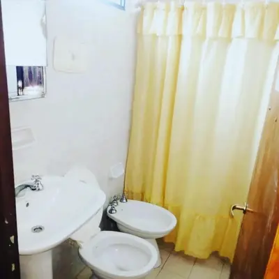 a bathroom with a white toilet and a sink at Complejo Villa del sol in Mina Clavero