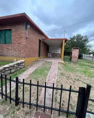 a brick house with a fence in front of it at Complejo Villa del sol in Mina Clavero