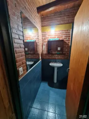 a bathroom with two sinks and a mirror and brick wall at Casa Sol Y Rio, LOFT MONOAMBIENTE in Mina Clavero