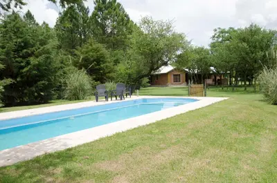 a swimming pool with two chairs in a yard at Yerba Buena casas de campo - Nono in Nono