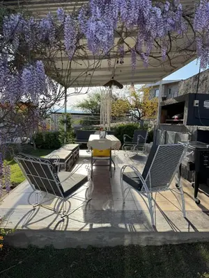 a patio with chairs and a table and purple wisteria at Casa en Estancia Vieja a 5 min del centro de Carlos Paz in Villa Carlos Paz