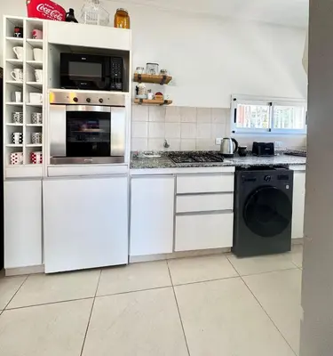 a kitchen with white cabinets and a washer and dryer at Casa en Estancia Vieja a 5 min del centro de Carlos Paz in Villa Carlos Paz
