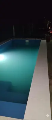 a blue and white swimming pool at night at La Morada de sus Sueños Caeiro in Bialet Massé