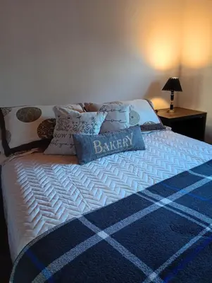 a bed with a blue and white blanket and pillows at Balcones del Rio in Santa Rosa de Calamuchita