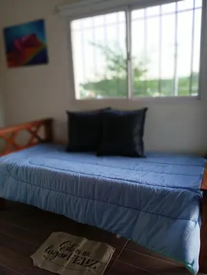 a bed with a blue comforter in a bedroom at Balcones del Rio in Santa Rosa de Calamuchita