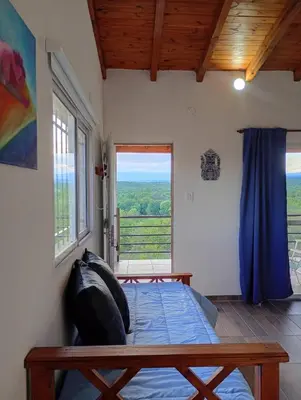 a bedroom with a bed and a large window at Balcones del Rio in Santa Rosa de Calamuchita