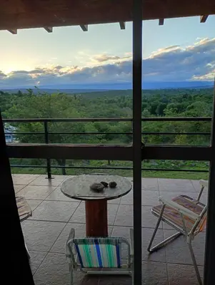 a table and chairs on a balcony with a view at Balcones del Rio in Santa Rosa de Calamuchita
