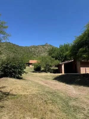 a house in a field with a mountain in the background at Cabañas De La Colina in Villa General Belgrano