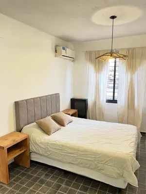 a bedroom with a bed and a table and a window at Casa alquiler temporario, Cerro, Córdoba in Cordoba