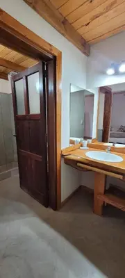 a bathroom with a wooden door and a sink at Aldea de los Cerros in Villa Yacanto